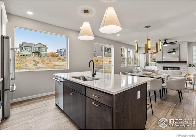 kitchen featuring dark brown cabinetry, sink, a brick fireplace, and pendant lighting