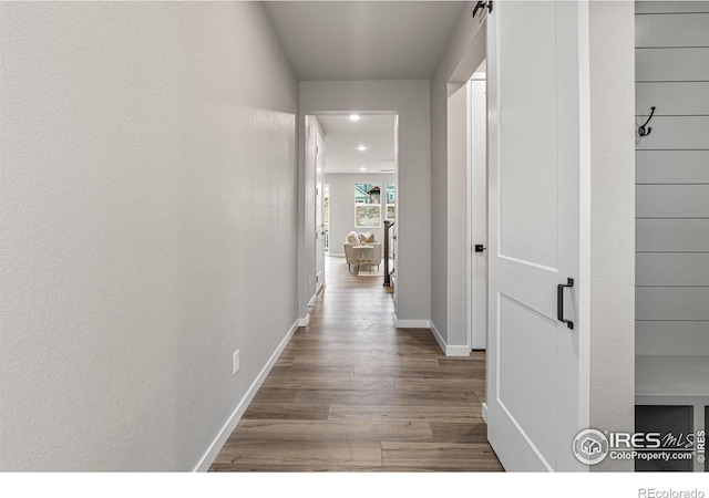 corridor with light hardwood / wood-style floors and a barn door