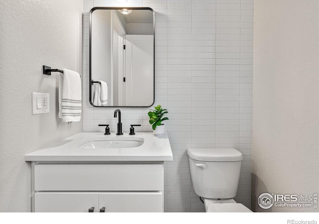 bathroom featuring tile walls, vanity, and toilet