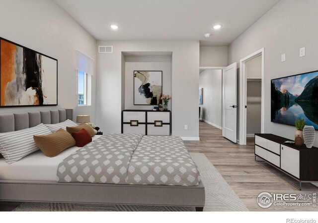 bedroom featuring a closet, light hardwood / wood-style flooring, and a walk in closet