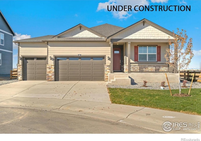 craftsman house with a garage, driveway, a porch, stone siding, and a front yard