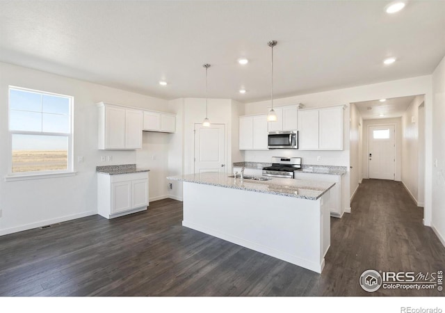 kitchen with dark wood-type flooring, appliances with stainless steel finishes, a kitchen island with sink, and white cabinets