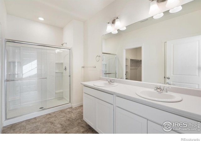 bathroom featuring a stall shower, double vanity, and a spacious closet