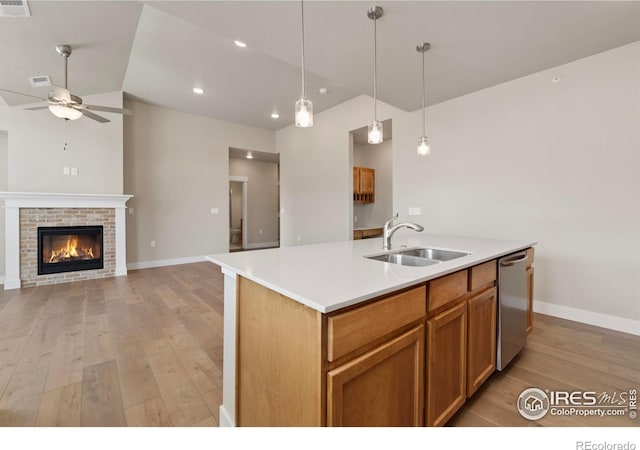 kitchen with pendant lighting, sink, light hardwood / wood-style flooring, a kitchen island with sink, and stainless steel dishwasher