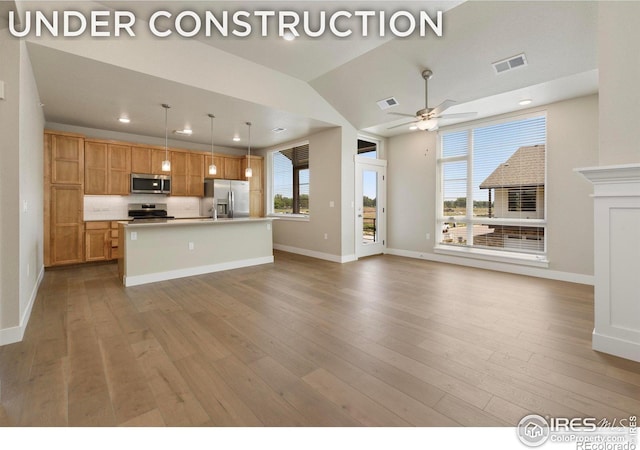 kitchen featuring pendant lighting, stainless steel appliances, a kitchen island with sink, and light wood-type flooring