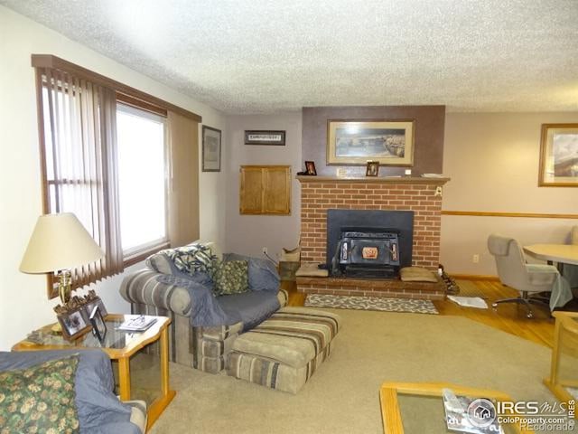 living room with a textured ceiling, a wood stove, and hardwood / wood-style floors