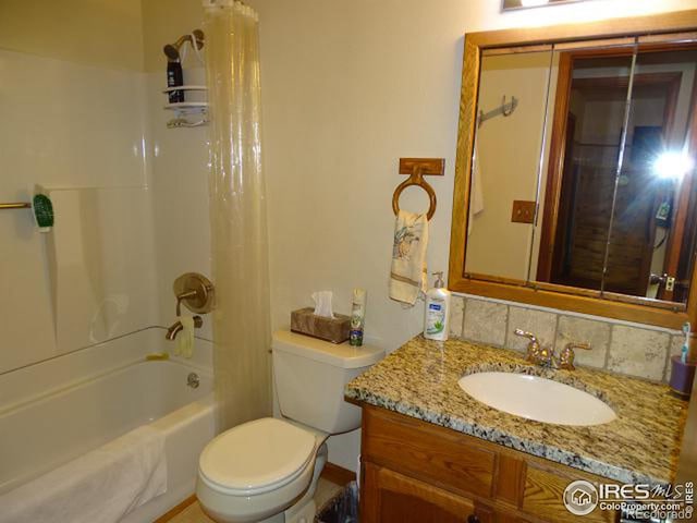 full bathroom with vanity, toilet, shower / bath combo with shower curtain, and backsplash