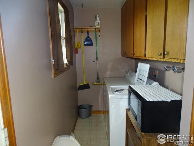 washroom featuring cabinets and washer and clothes dryer