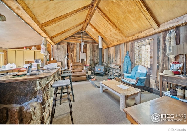 carpeted living room with vaulted ceiling with beams, a wood stove, and wood walls