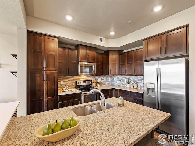 kitchen featuring a breakfast bar area, sink, appliances with stainless steel finishes, and light stone counters