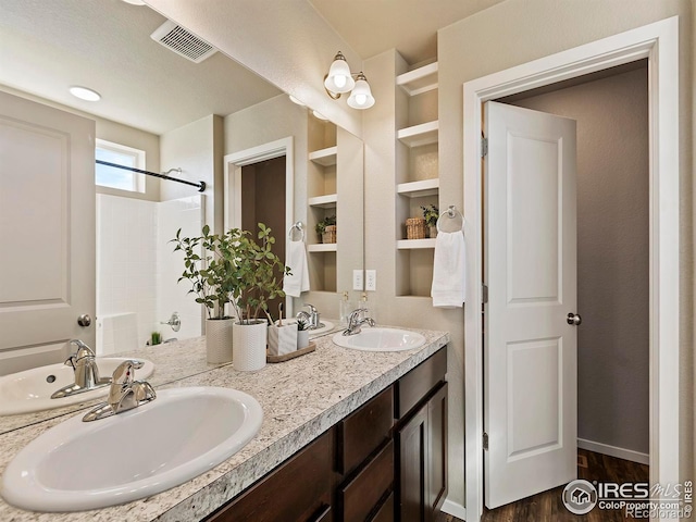 bathroom featuring vanity, walk in shower, wood-type flooring, and built in features