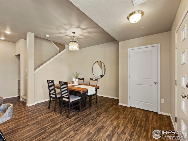 dining area with a textured ceiling, an inviting chandelier, and dark hardwood / wood-style floors