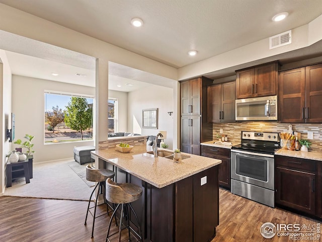 kitchen with a breakfast bar area, stainless steel appliances, sink, and dark hardwood / wood-style flooring