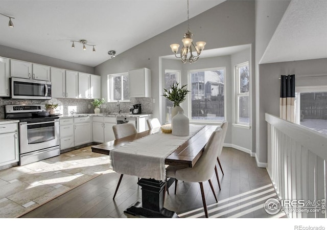 dining space featuring vaulted ceiling, sink, a notable chandelier, and light wood-type flooring