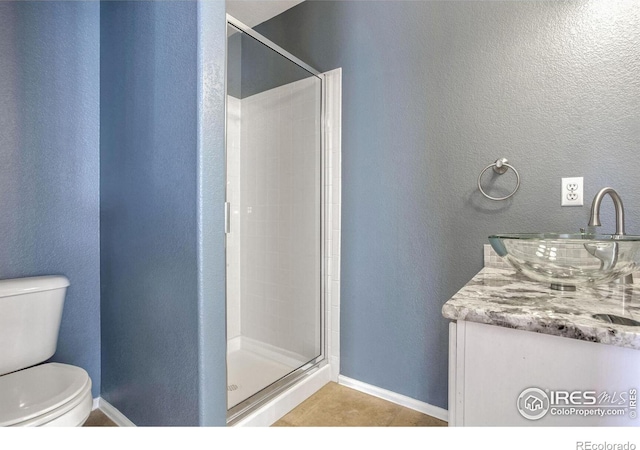 bathroom featuring a shower with door, vanity, tile patterned floors, and toilet