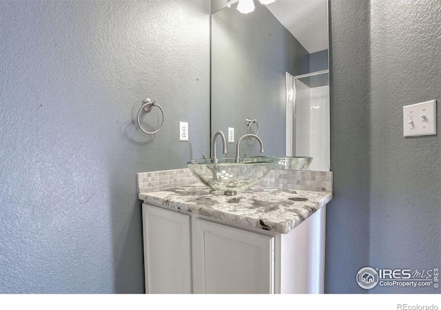 bathroom featuring vanity and backsplash