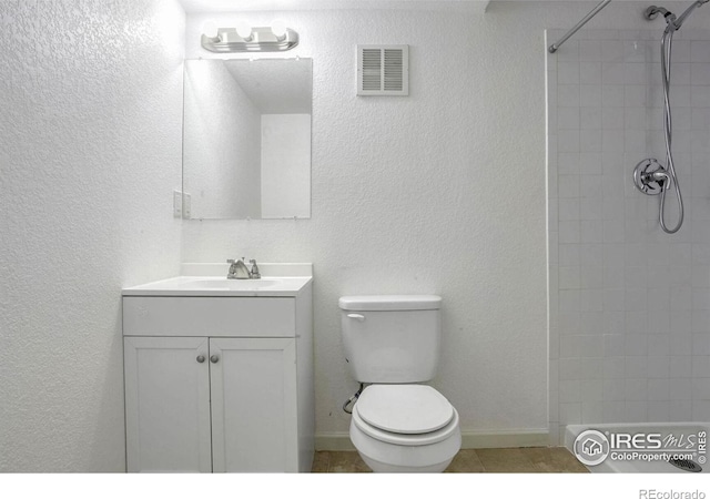 bathroom with vanity, toilet, and a tile shower