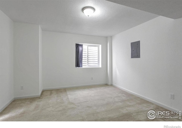 empty room featuring light carpet, electric panel, and a textured ceiling