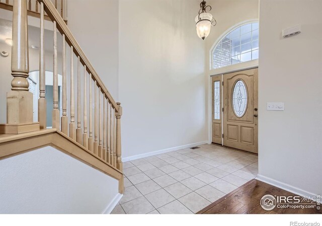18715 Wagon Trl, Mead, CO 80542 - entryway with a high ceiling, baseboards, stairway, and light tile patterned flooring