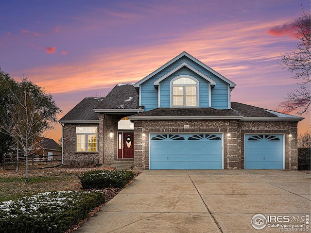 traditional home featuring driveway, a shingled roof, an attached garage, and brick siding