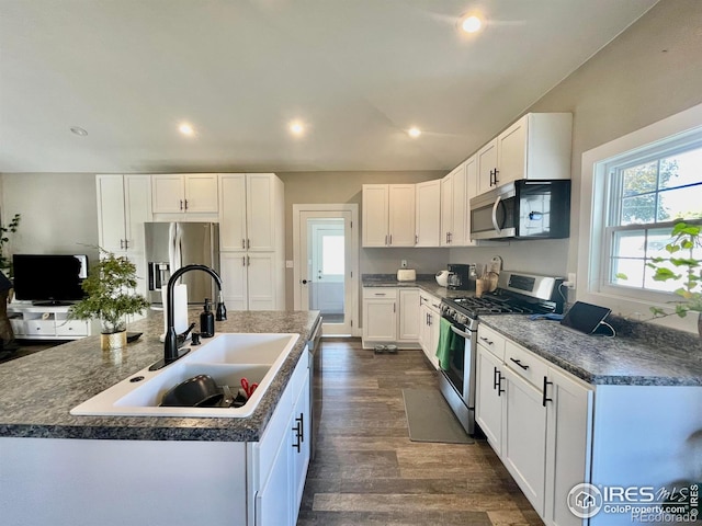 304 S High School Ave, Holyoke, CO 80734 - kitchen featuring stainless steel appliances, an island with sink, dark wood-style floors, white cabinetry, and dark countertops