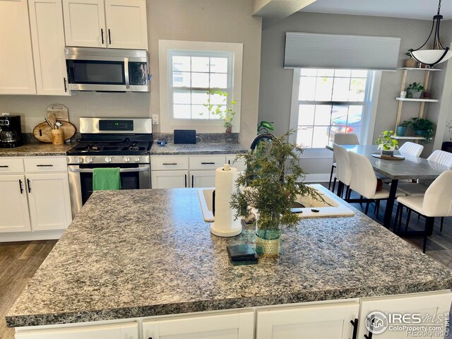 304 S High School Ave, Holyoke, CO 80734 - kitchen featuring appliances with stainless steel finishes, a kitchen island, dark wood-style floors, and white cabinetry