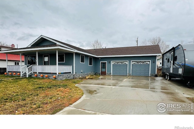 view of front of property featuring covered porch, a garage, and a front lawn