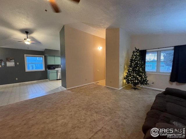 unfurnished living room featuring lofted ceiling, a healthy amount of sunlight, light carpet, and ceiling fan