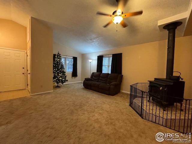 carpeted living room with lofted ceiling, ceiling fan, a textured ceiling, and a wood stove