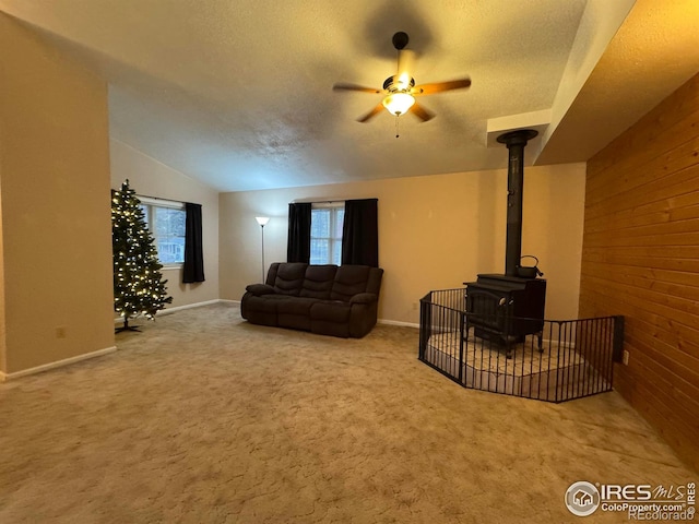 carpeted living room featuring lofted ceiling, a wood stove, a textured ceiling, and wood walls