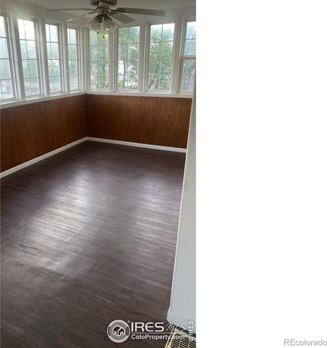 empty room featuring wooden walls, dark hardwood / wood-style floors, and ceiling fan