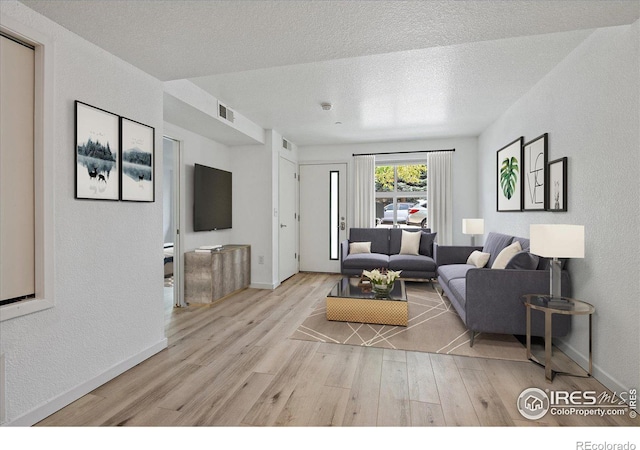 living room with a textured ceiling and light hardwood / wood-style floors