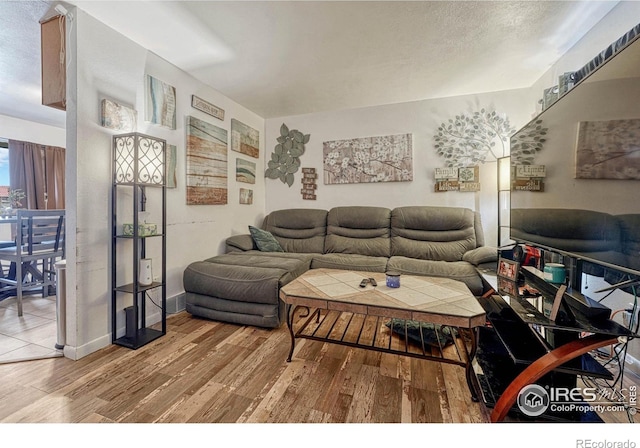 living room with a textured ceiling, baseboards, and wood finished floors