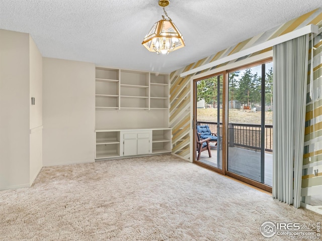 unfurnished living room featuring a textured ceiling, a notable chandelier, and carpet flooring