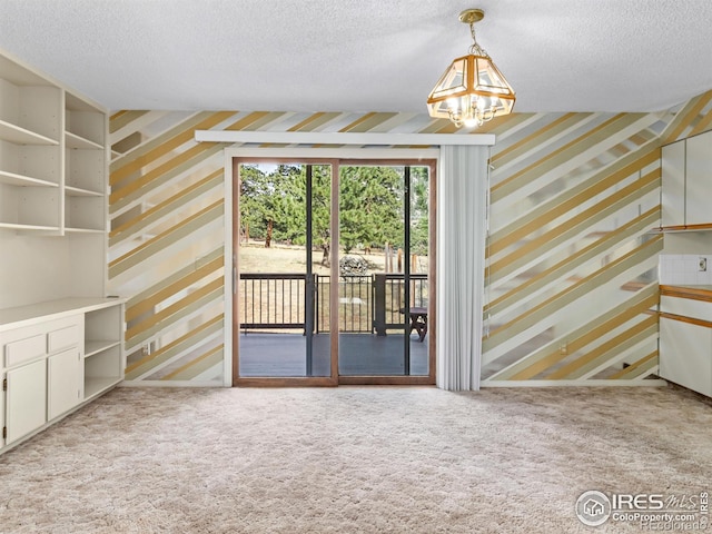 unfurnished living room featuring light carpet, a notable chandelier, and a textured ceiling