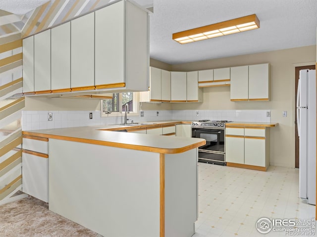 kitchen with sink, kitchen peninsula, white cabinetry, stove, and white fridge