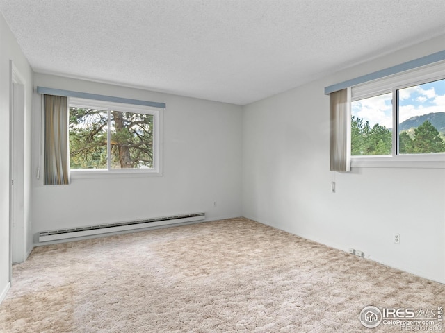 carpeted spare room with a baseboard heating unit and a textured ceiling