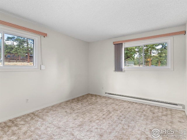 empty room featuring a textured ceiling, baseboard heating, and carpet