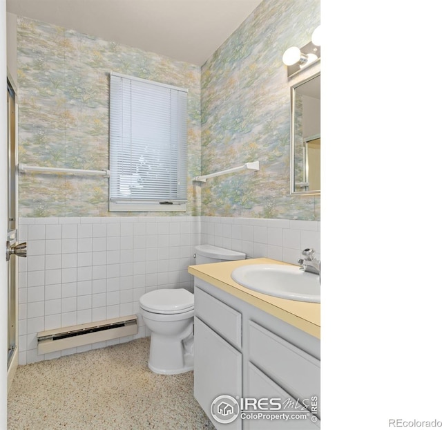 bathroom featuring vanity, baseboard heating, toilet, and tile walls