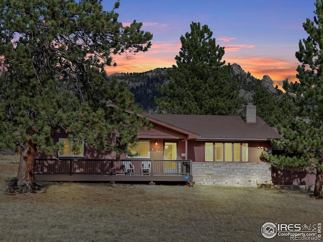 view of front of house featuring a deck with mountain view and a yard