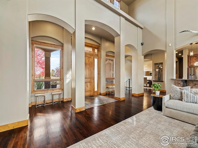 living room featuring a towering ceiling and dark hardwood / wood-style floors