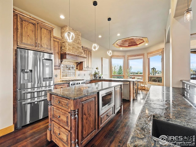 kitchen with stainless steel appliances, tasteful backsplash, pendant lighting, and dark hardwood / wood-style floors