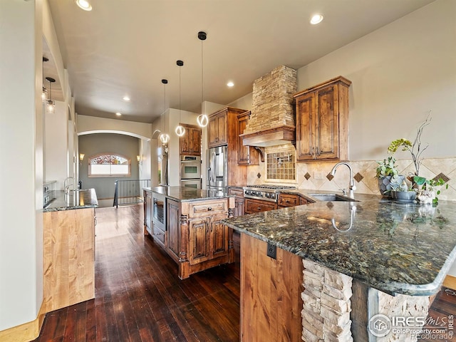 kitchen with dark hardwood / wood-style flooring, dark stone countertops, sink, pendant lighting, and a center island