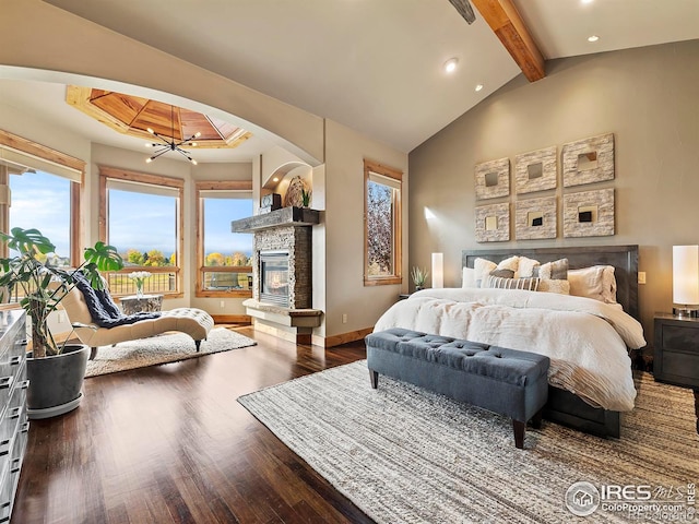 bedroom featuring vaulted ceiling with beams, a stone fireplace, dark hardwood / wood-style floors, and an inviting chandelier