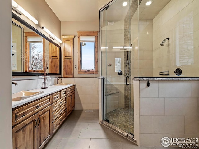 bathroom with vanity, tile walls, tile patterned flooring, and a shower with door