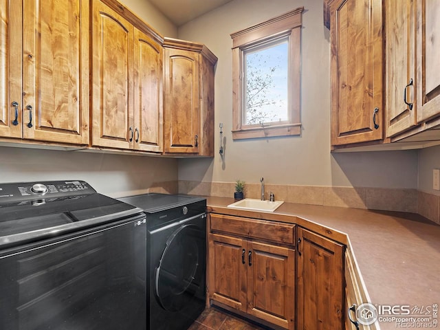 laundry room with sink, washing machine and clothes dryer, and cabinets