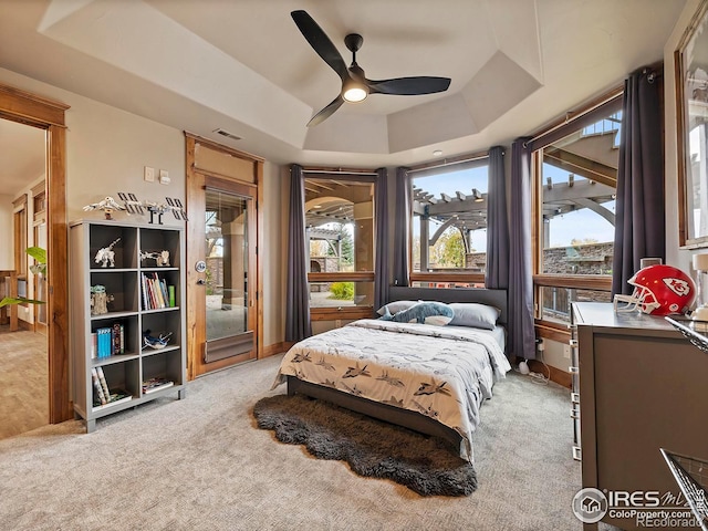 bedroom featuring ceiling fan, a raised ceiling, and light colored carpet