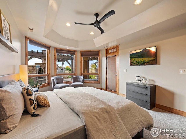 carpeted bedroom with a tray ceiling and ceiling fan