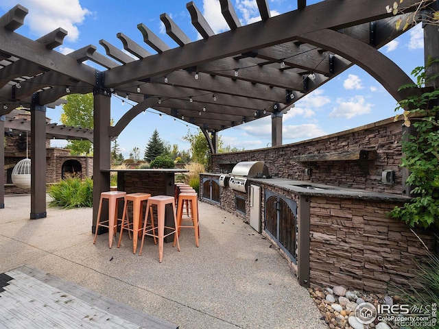 view of patio with exterior kitchen, exterior bar, grilling area, and a pergola