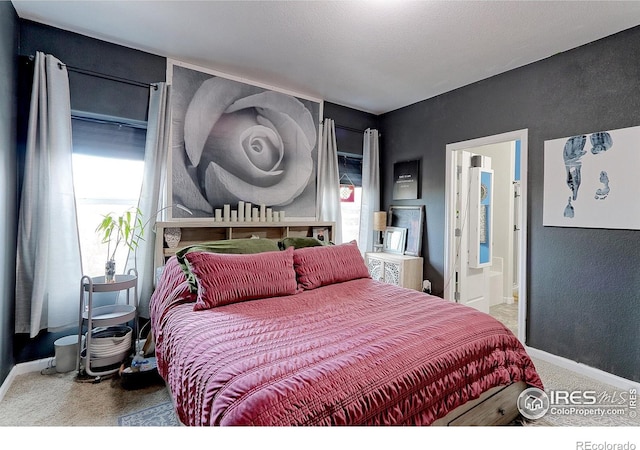 bedroom with a textured ceiling, carpet floors, and ensuite bath